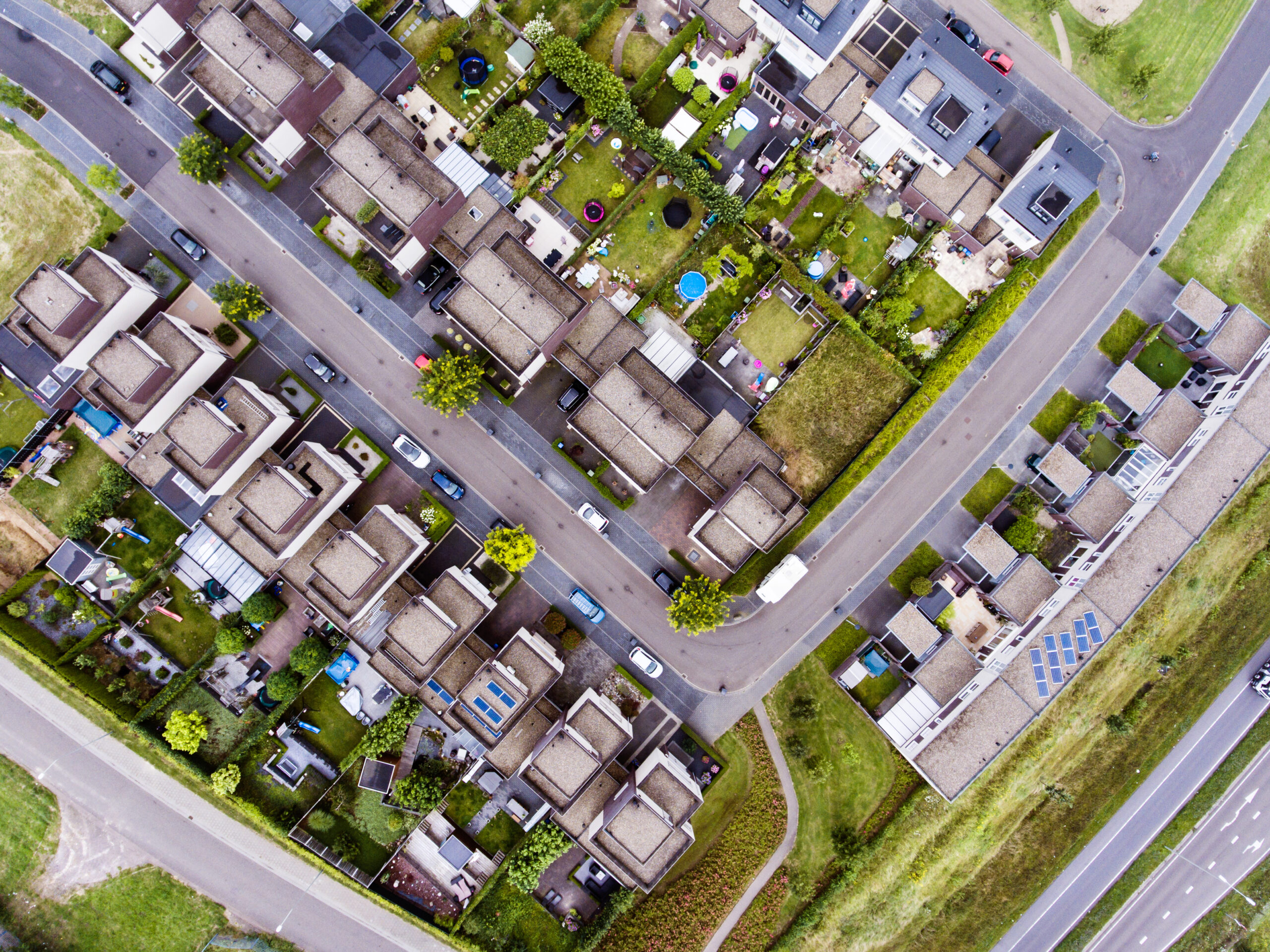 Aerial view of Dutch street with white houses and cars.