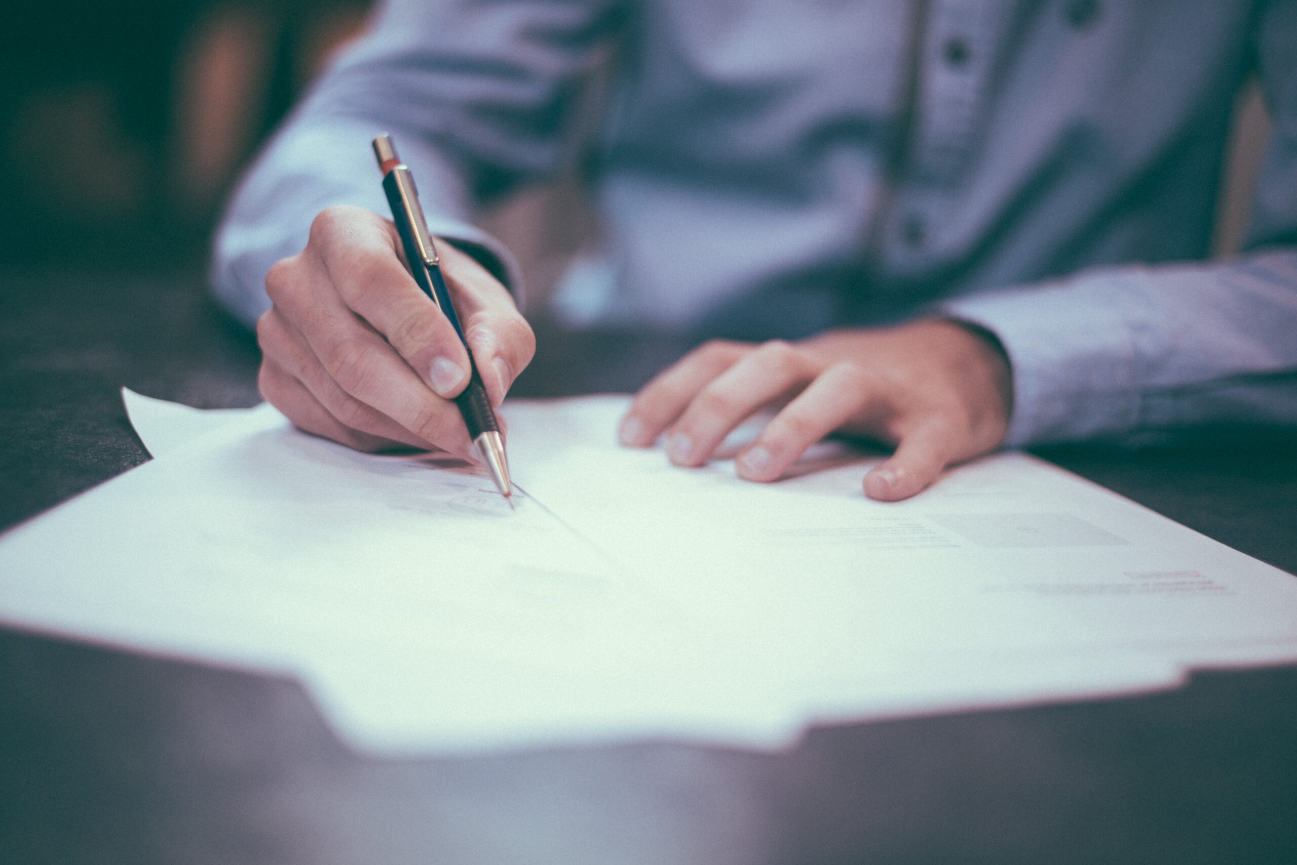 Person signing a document on a table